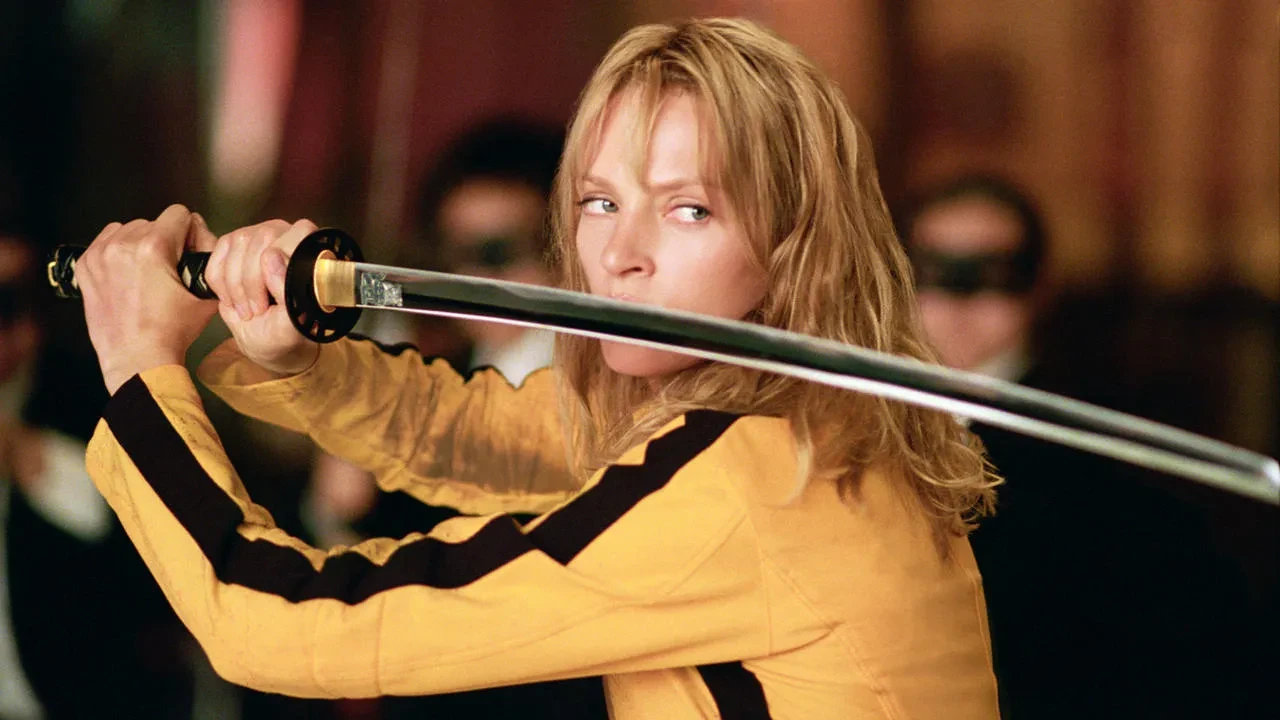 Uma Thurman en combinaison jaune à bande noire, brandissant un katana dans Kill Bill