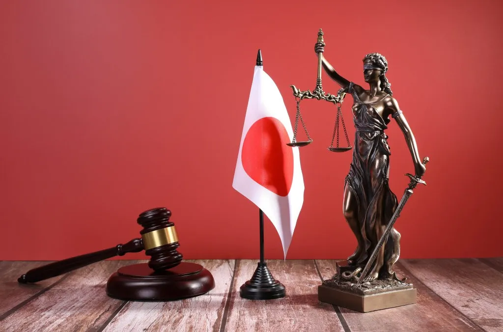 Statue de la Justice, marteau de juge et drapeau japonais sur fond rouge