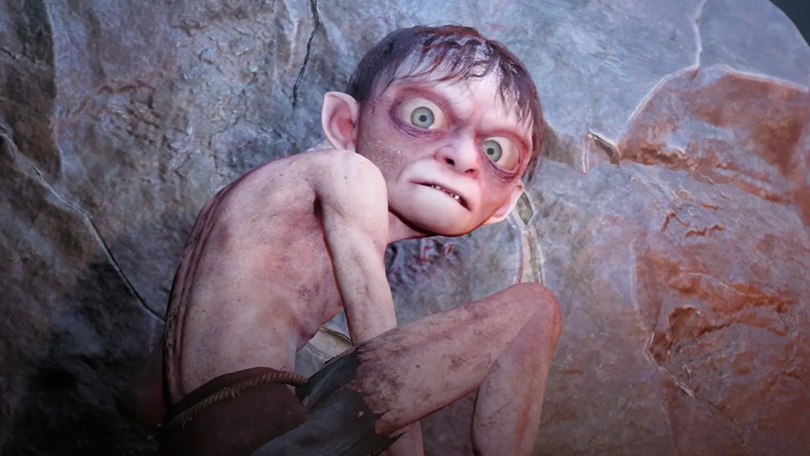Gollum accroupi contre un rocher, les yeux écarquillés, dans le jeu Le Seigneur des anneaux : Gollum