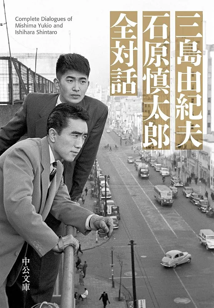 Couverture de livre montrant une photographie en noir et blanc de Yukio Mishima et Shintarō Ishihara, en veste, accoudés à une rambarde au-dessus d'une avenue urbaine, avec le titre en japonais.