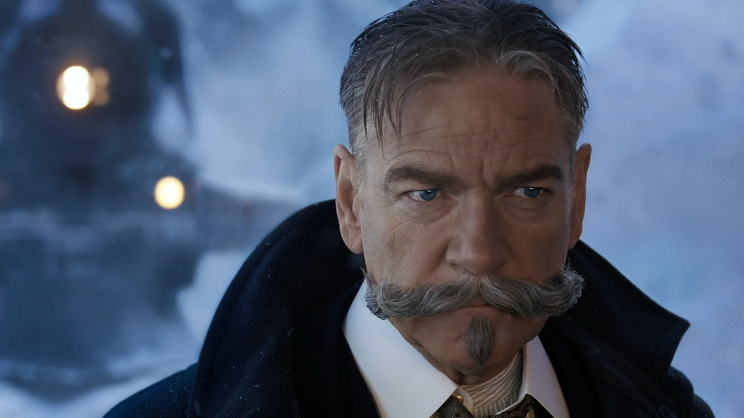 Kenneth Branagh en Hercule Poirot, moustache grise, devant un train dans la neige
