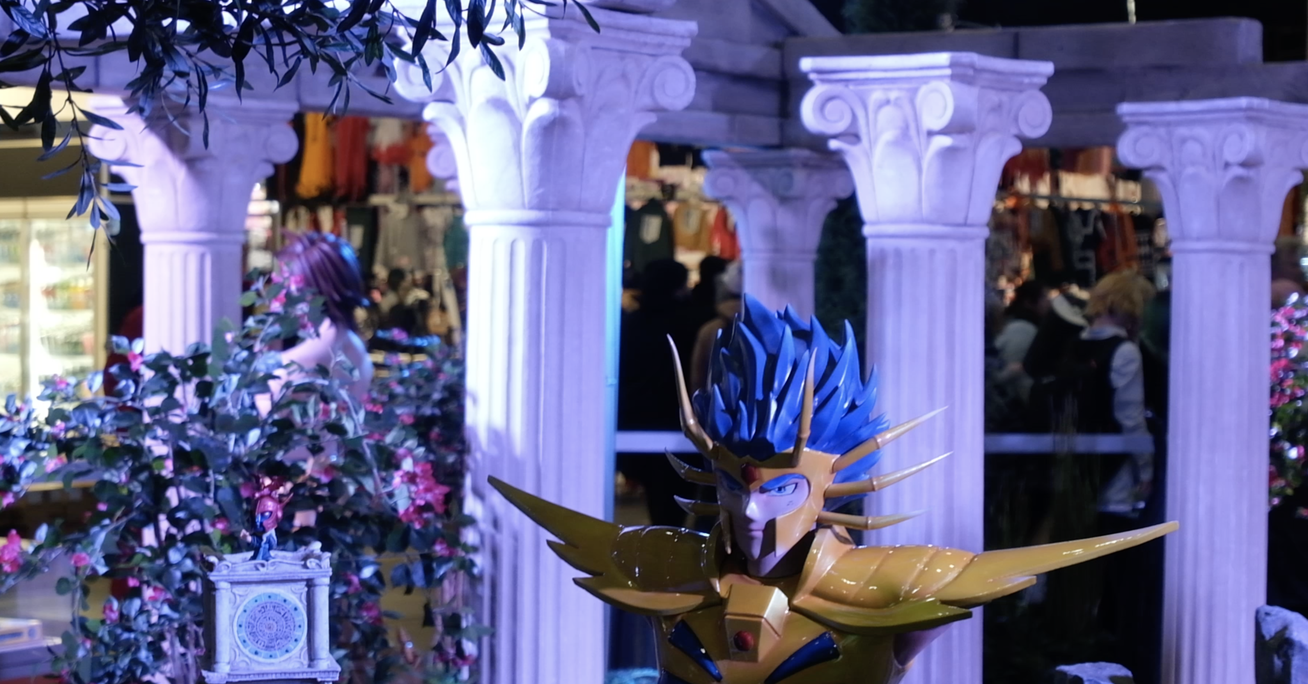 Buste géant d’un chevalier d’or au casque à pointes et aux cheveux bleus, entre des colonnes
