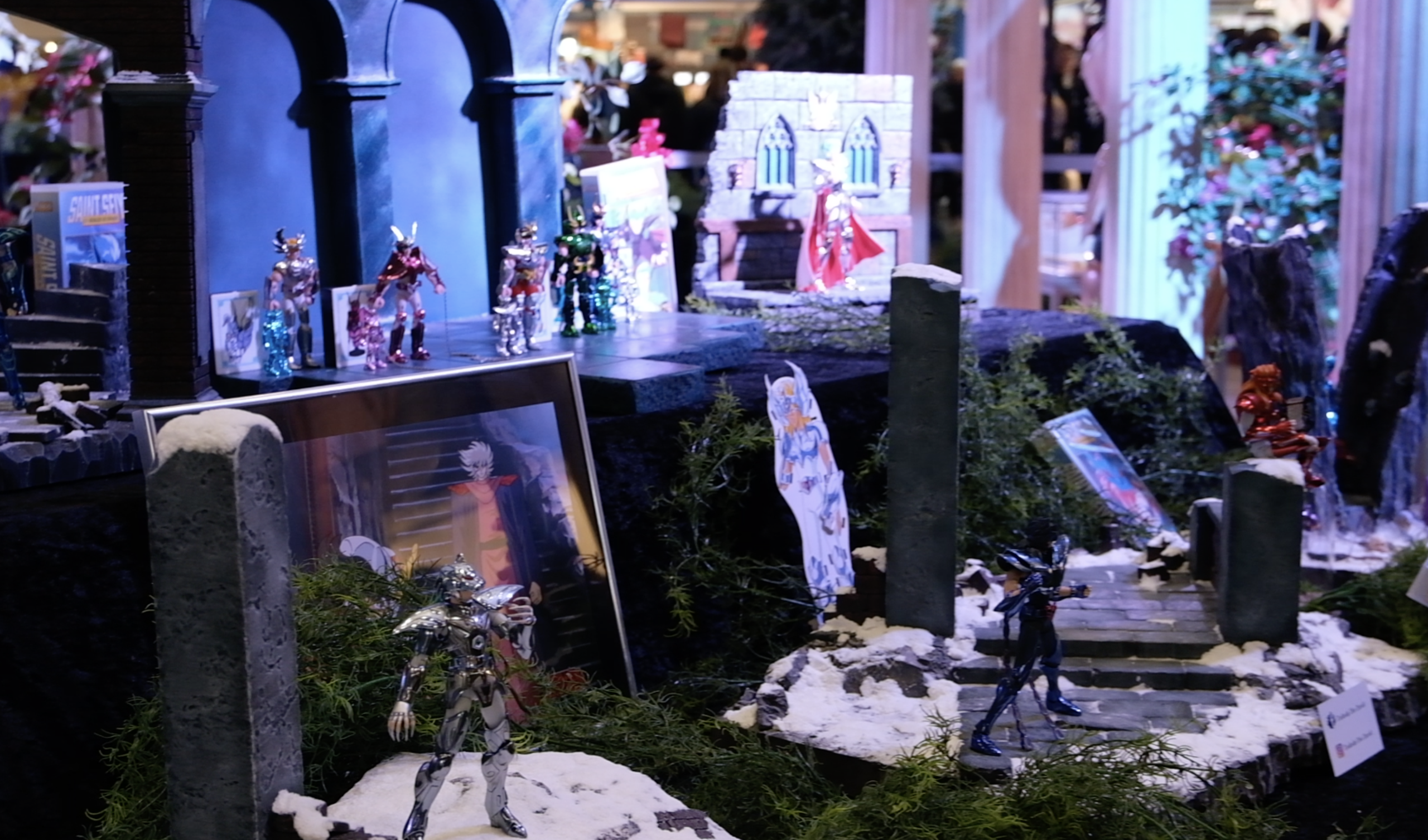 Figurines de chevaliers dans un décor enneigé, devant une illustration encadrée de l’anime