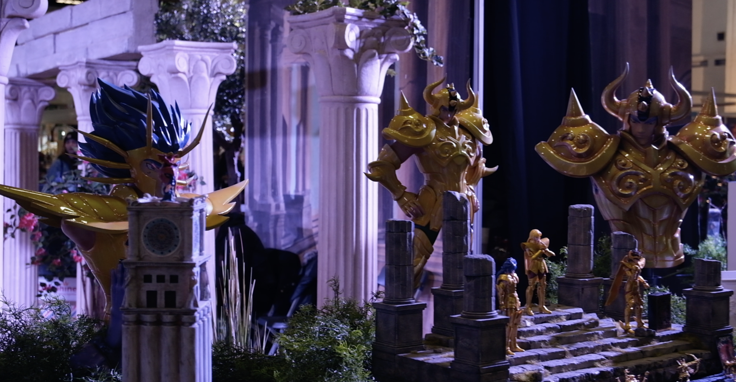 Statues de chevaliers d’or entre des colonnes grecques, devant un escalier en ruine miniature