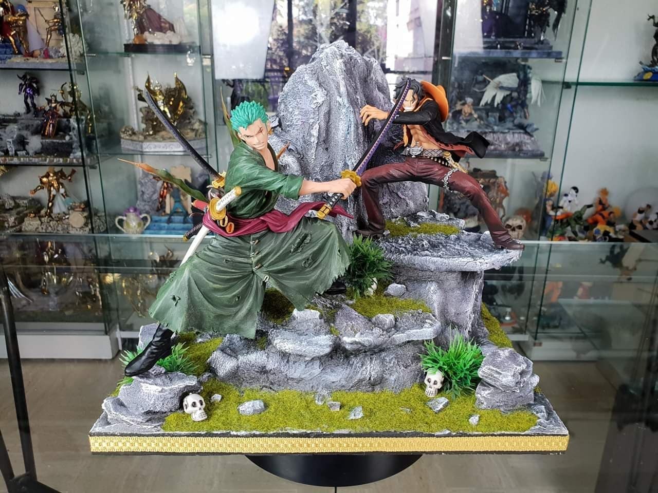 Diorama One Piece&nbsp;: Zoro croise le sabre avec un pirate au chapeau orange sur un rocher