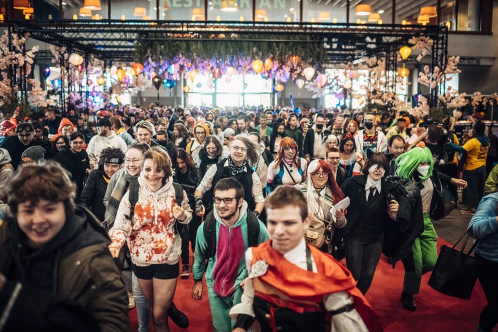 Foule de visiteurs et de cosplayeurs entrant en courant dans le hall d’un salon
