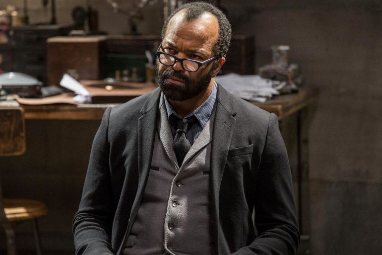Jeffrey Wright en costume sombre et lunettes, assis devant un bureau