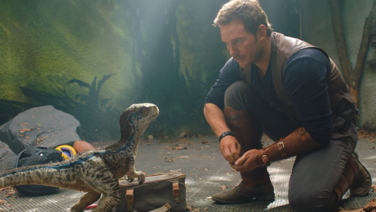 Owen, accroupi, face au jeune vélociraptor Blue