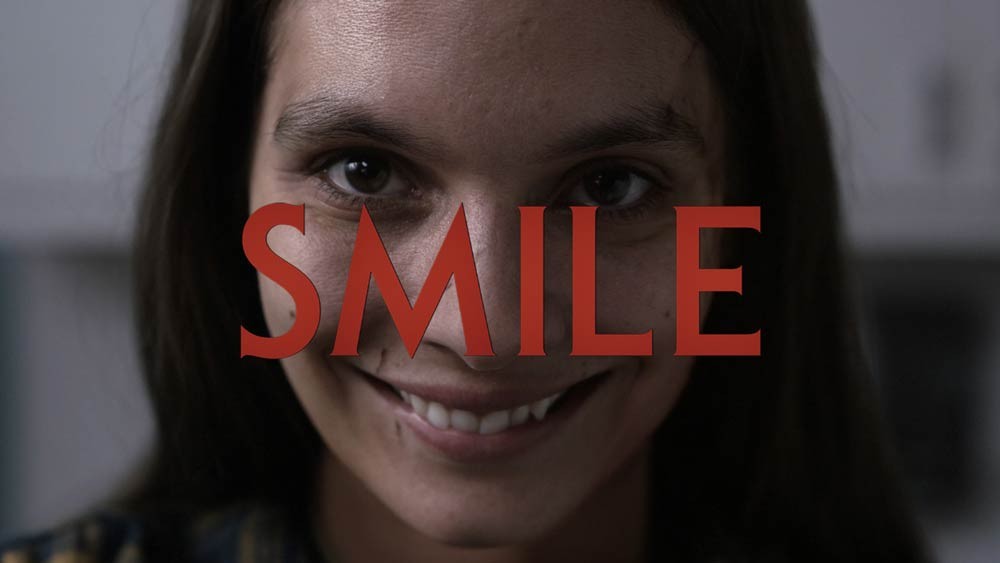 Titre Smile en lettres rouges sur le visage d’une femme au sourire inquiétant