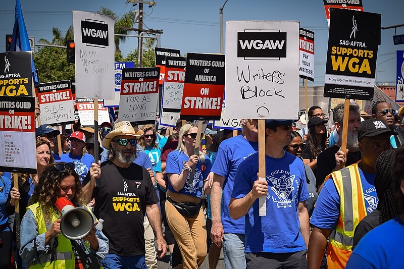 Manifestants de la WGA et de la SAG-AFTRA défilant avec des pancartes « On Strike! » sous le soleil