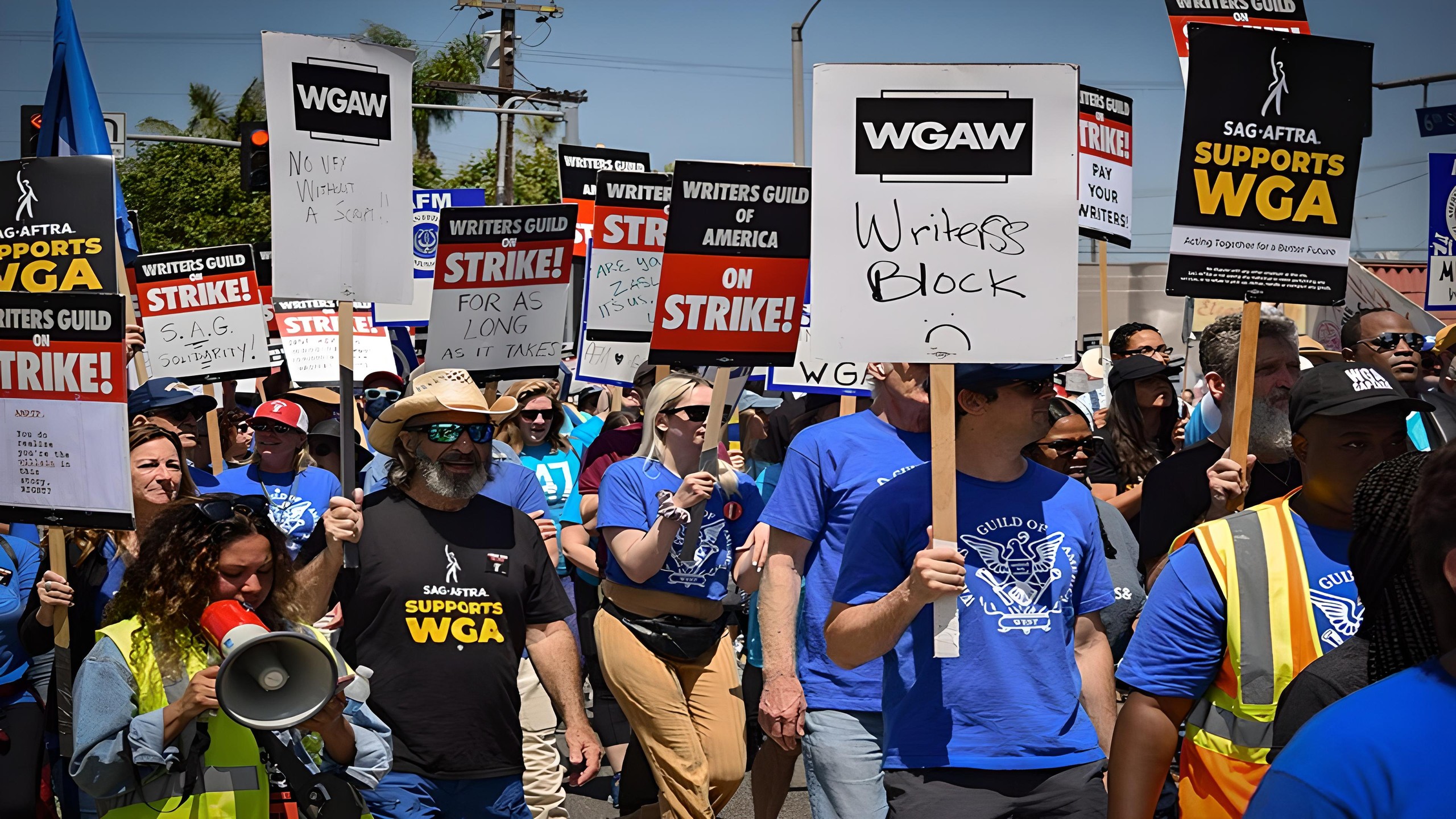 Manifestants de la Writers Guild of America en grève, pancartes«&nbsp;On strike!&nbsp;» et«&nbsp;SAG-AFTRA supports WGA&nbsp;»