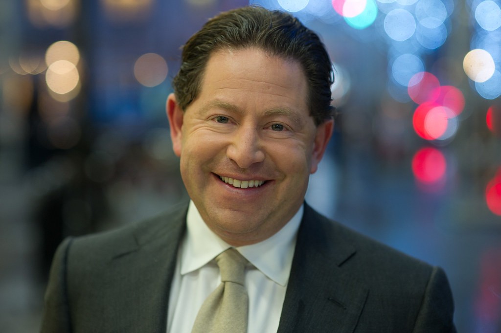Portrait souriant de Bobby Kotick en costume, devant des lumières de ville floues