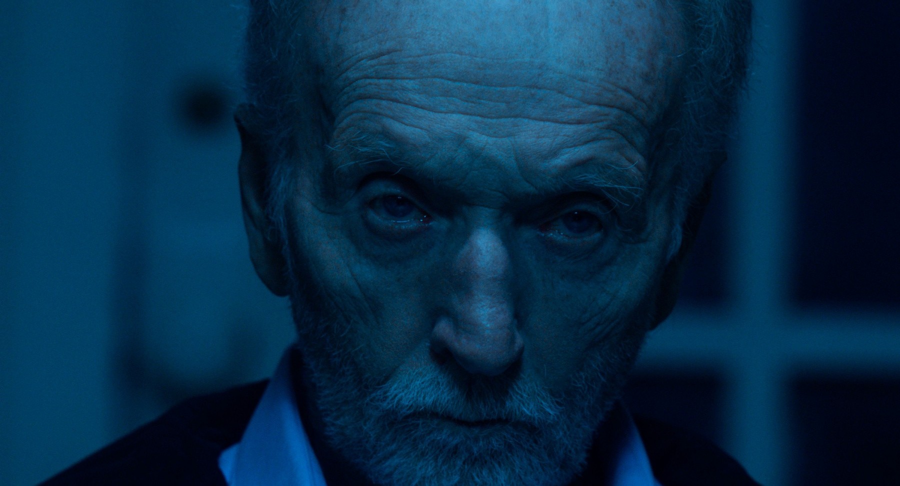 John Kramer, joué par Tobin Bell, fixe l’objectif dans une pénombre bleutée
