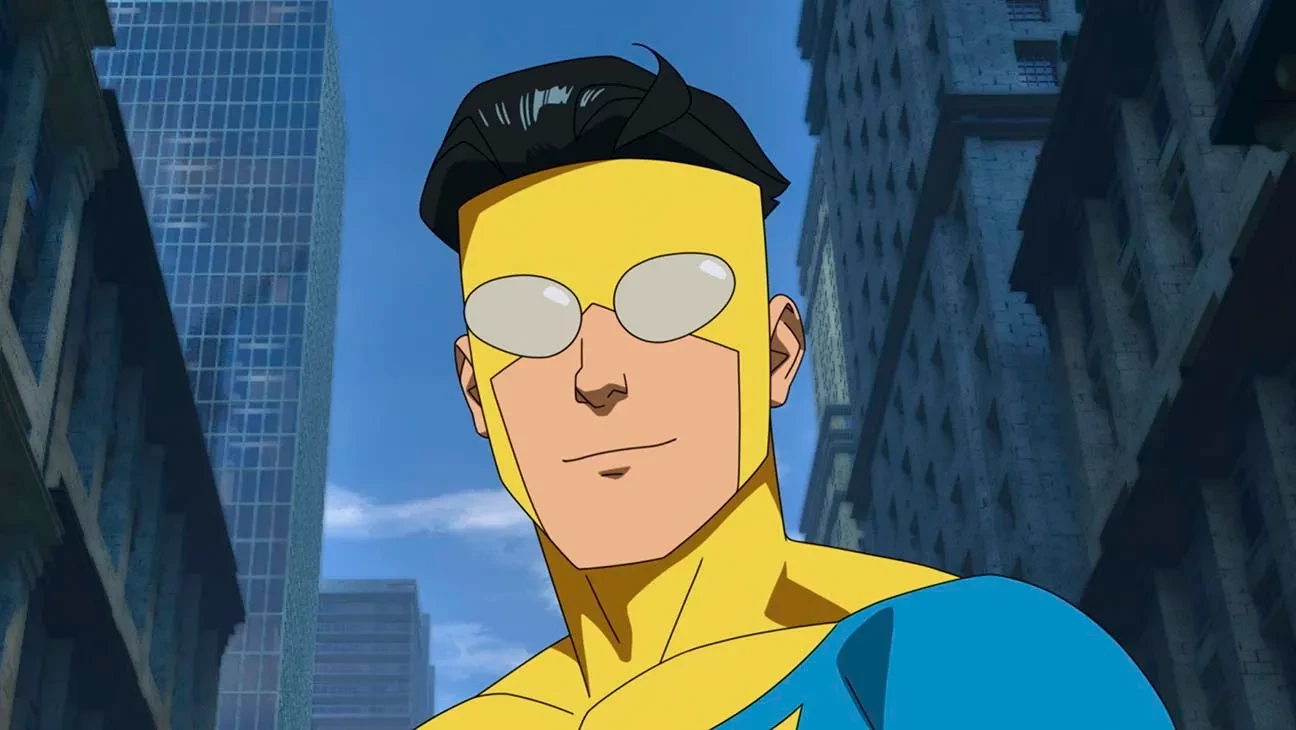 Invincible, en costume jaune et bleu, sourit entre les gratte-ciel