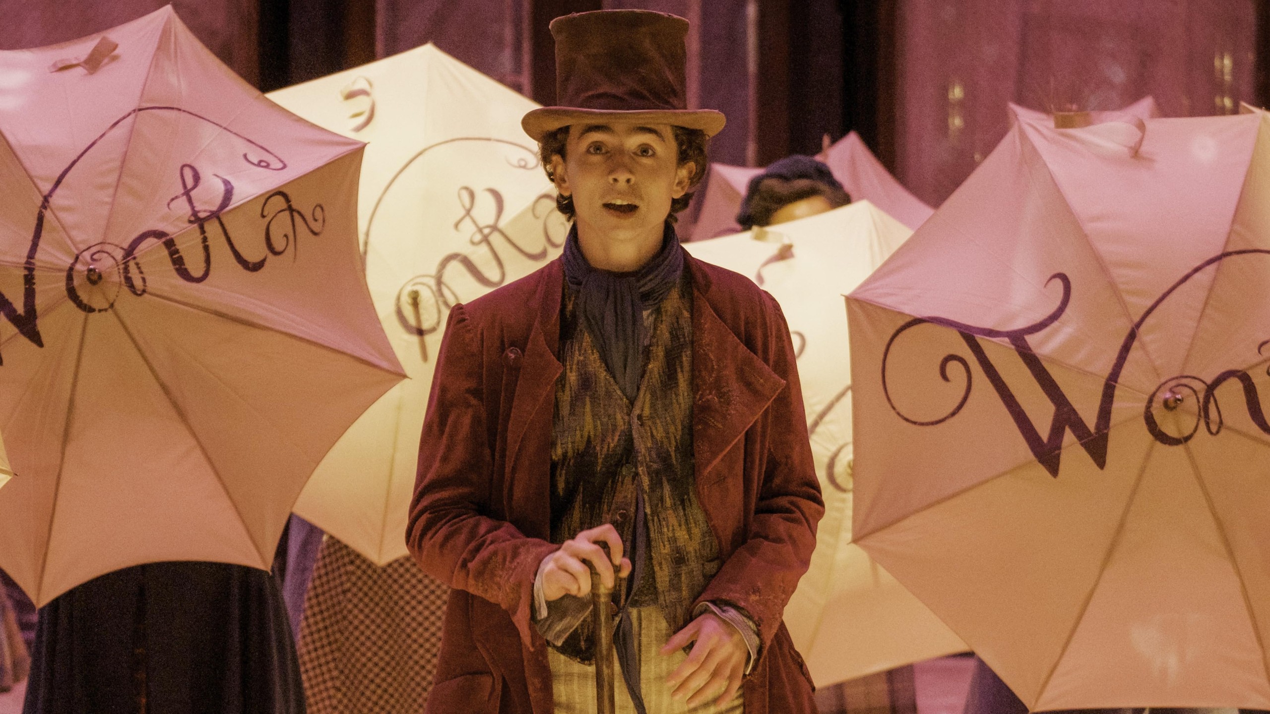 Willy Wonka en haut-de-forme, entouré d’ombrelles roses portant son nom