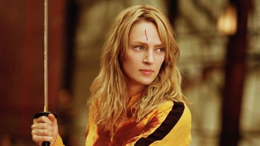Beatrix Kiddo, blessée au front et tachée de sang, tient son sabre levé