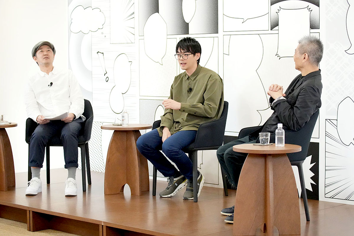 Trois hommes assis discutent sur une scène décorée de cases de manga, lors de l’entretien de Hobonichi