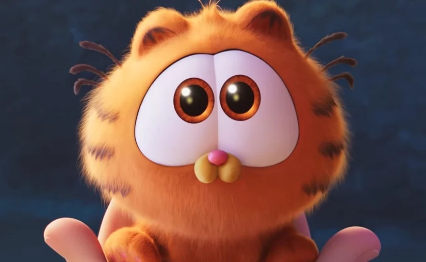 Garfield bébé, aux grands yeux ronds, tenu dans des mains humaines