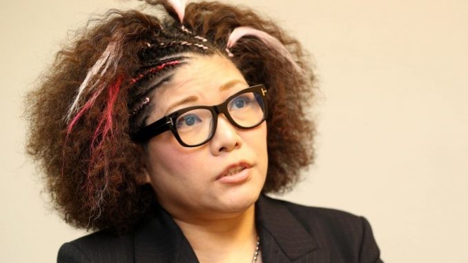 Kyoko Kimura, lunettes noires et cheveux bouclés, lors d’une interview