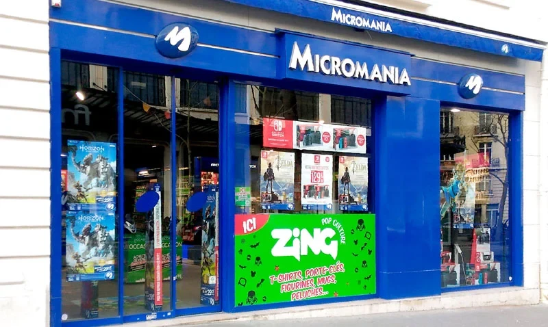 Façade bleue d’une boutique Micromania avec des affiches de jeux en vitrine