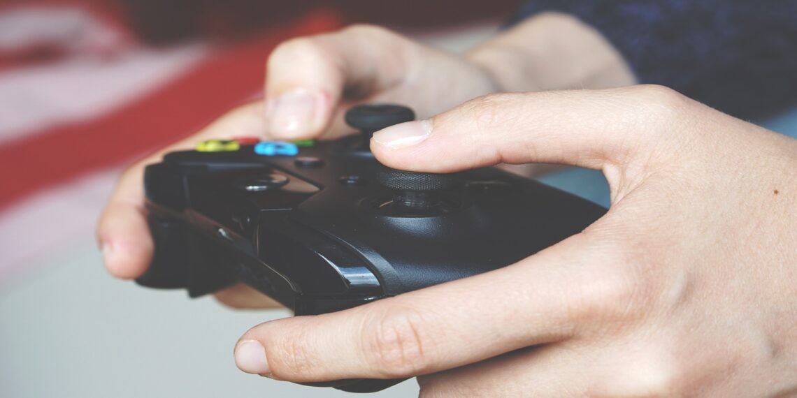 Gros plan sur deux mains tenant une manette de console noire