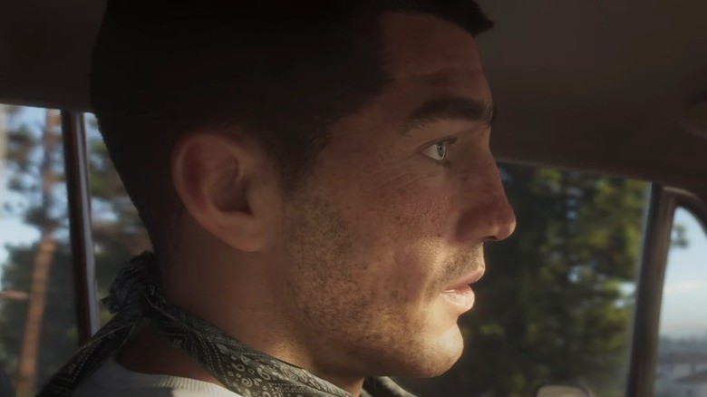 Jason de profil au volant d’une voiture, foulard autour du cou