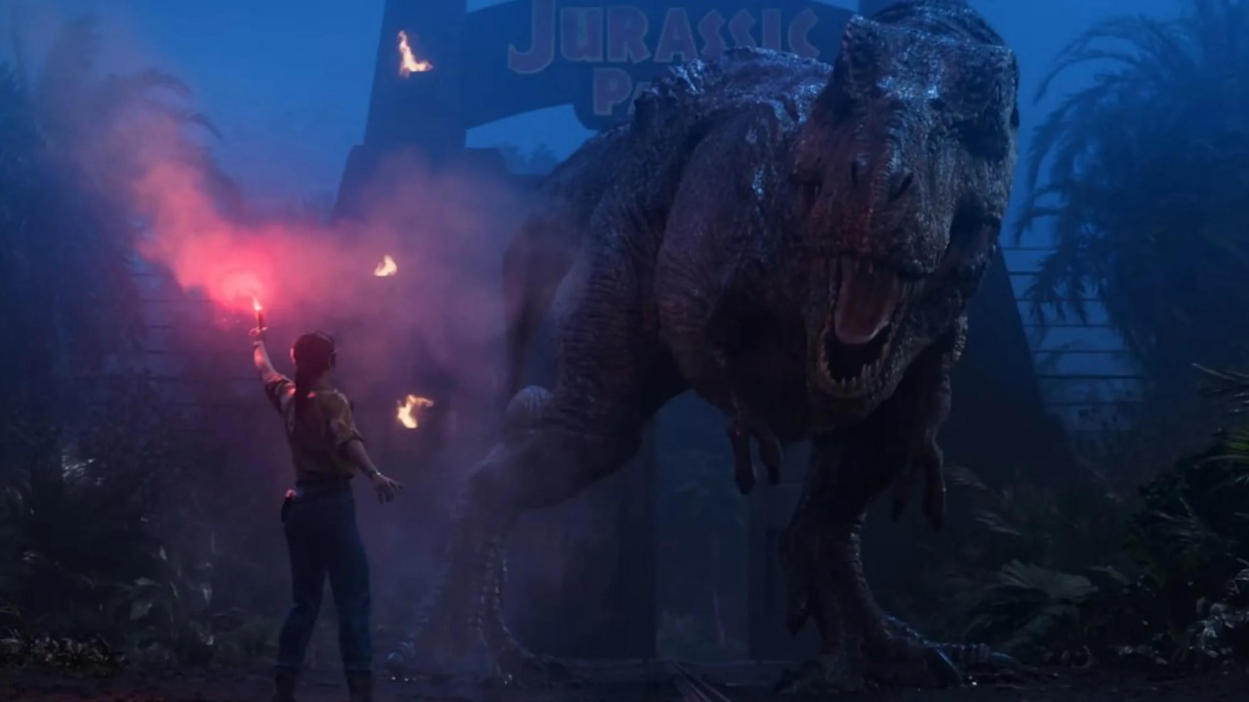Une femme brandit une torche rouge face à un tyrannosaure devant la porte de Jurassic Park