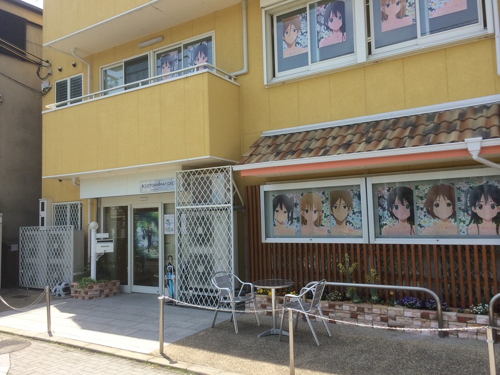 Façade jaune d’un bâtiment de Kyoto Animation, vitrines ornées de personnages d’anime
