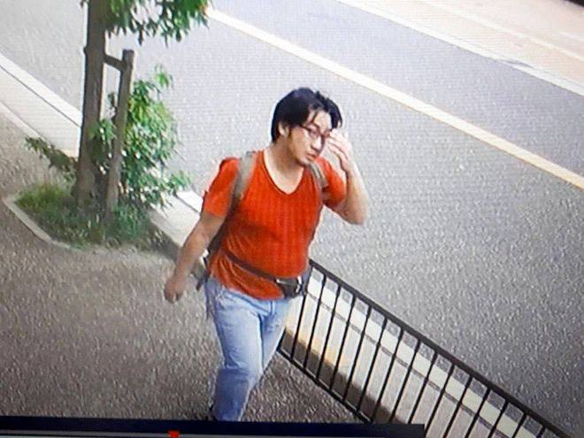 Capture de vidéosurveillance d’un homme en t-shirt orange marchant sur un trottoir