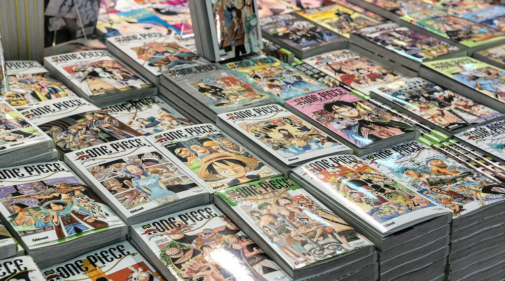 Piles de tomes du manga One Piece en édition Glénat sur un étal