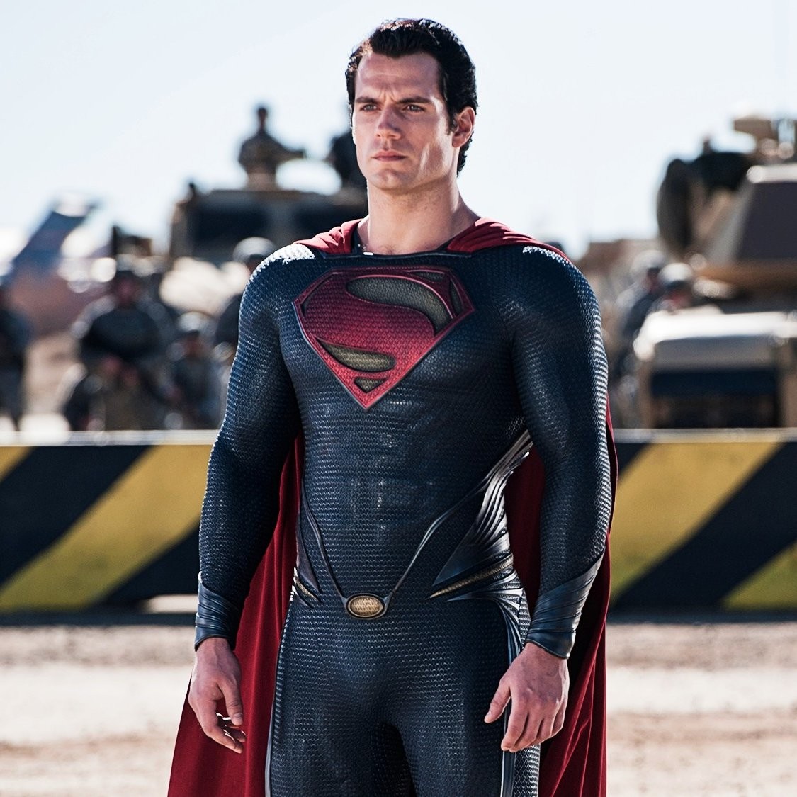 Henry Cavill en Superman, costume sombre et cape rouge, devant des militaires