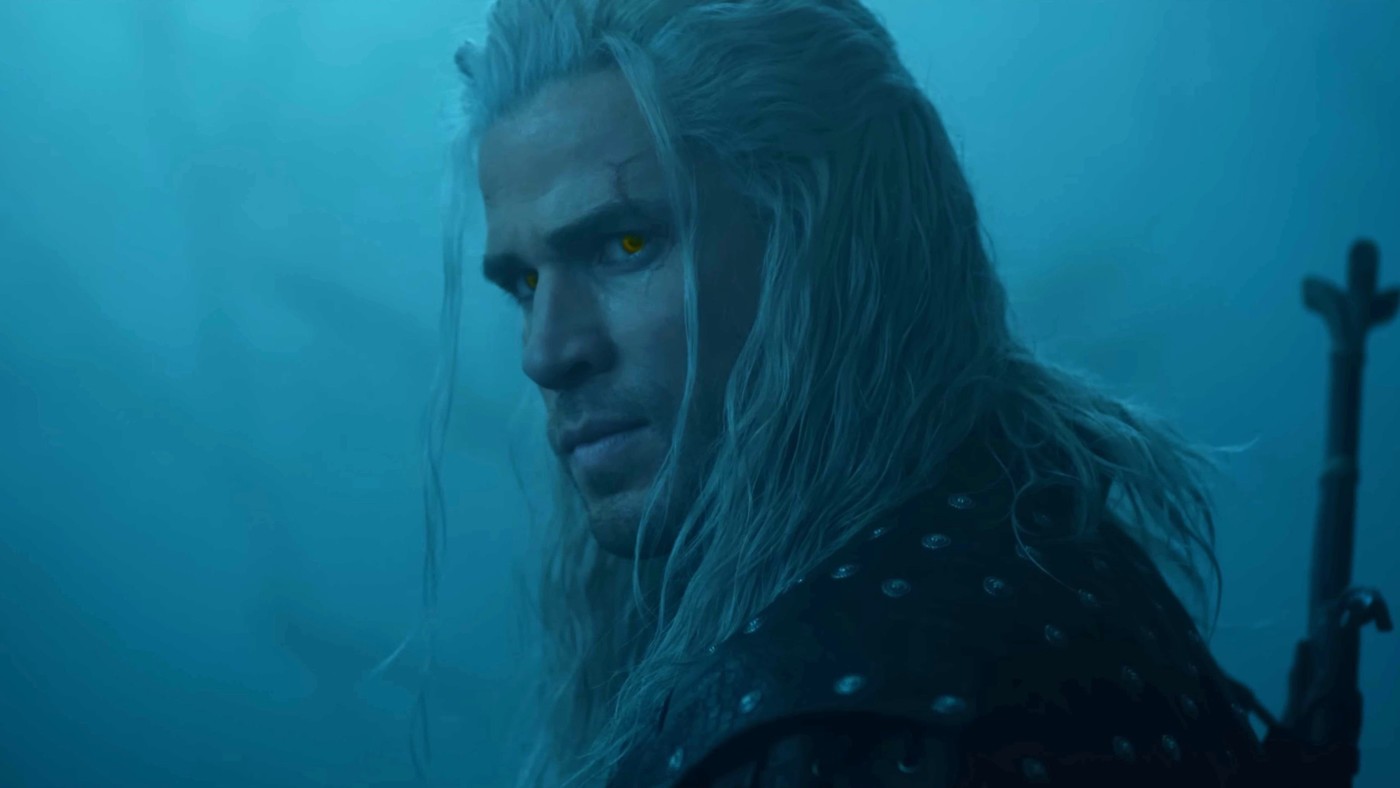 Liam Hemsworth en Geralt de Riv, cheveux blancs et yeux dorés, dans une brume bleutée
