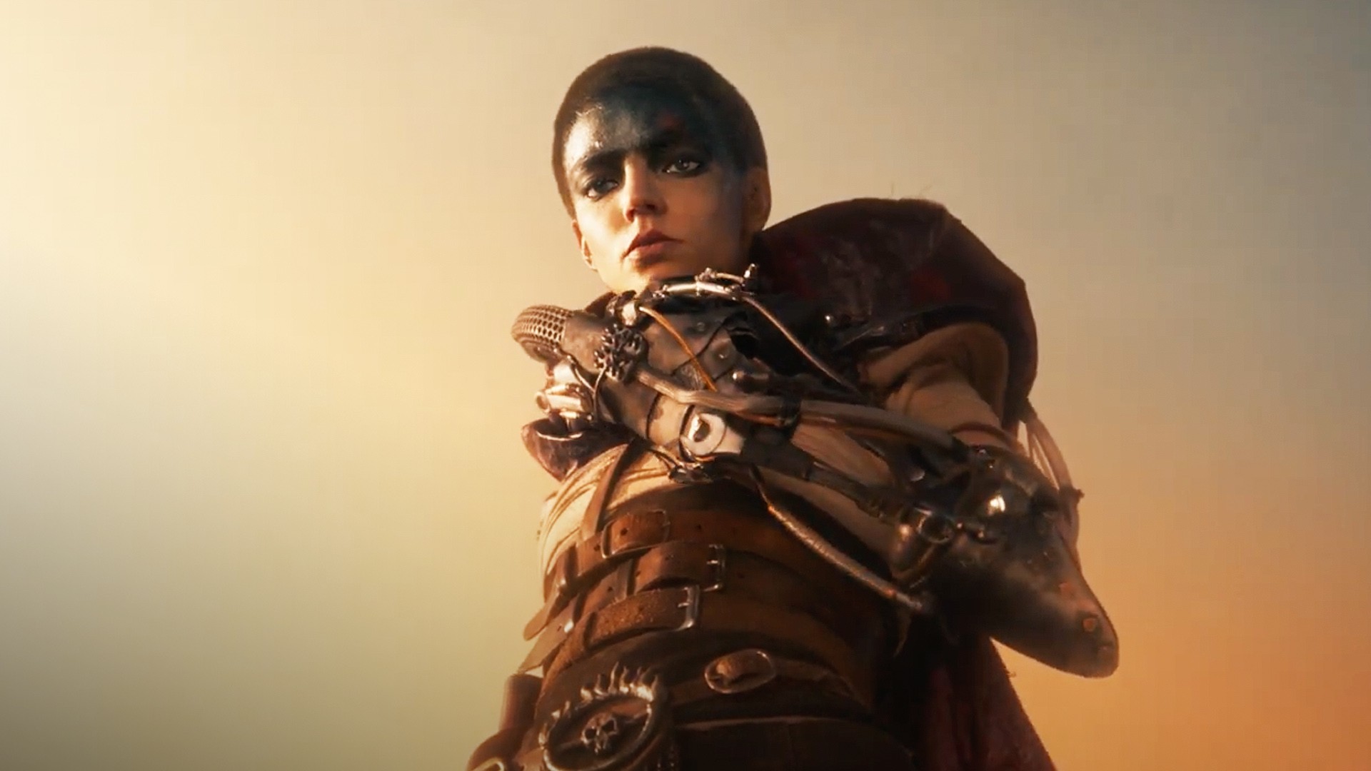 Furiosa, le visage maculé de noir, son bras mécanique replié contre la poitrine
